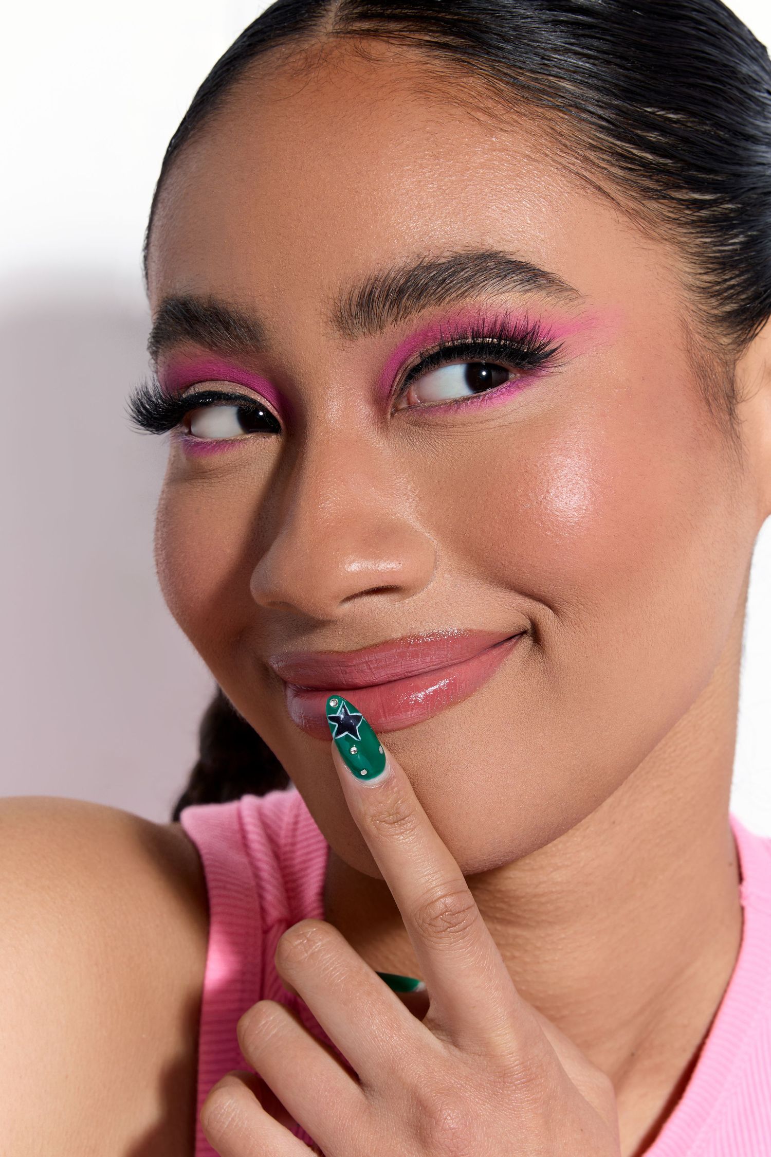 Close-up beauty shot featuring bright pink eye makeup and emerald jewelry.