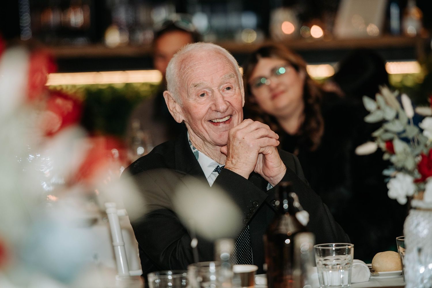 An elderly guest enjoying a joyful moment at a reception dinner with warm lighting and table settings.