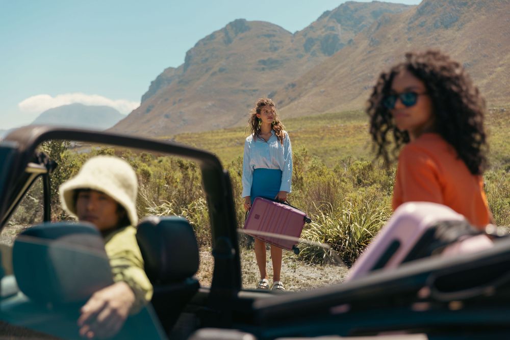 Group enjoying scenic mountain drive in convertible car with luggage.
