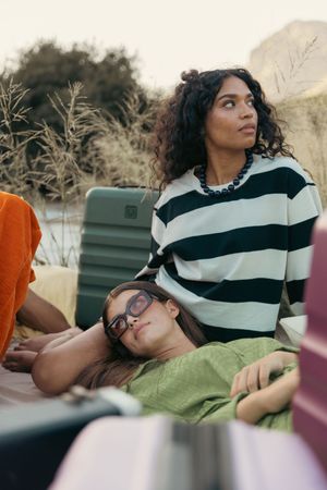 Friends relaxing outdoors with striped sweater and casual attire against natural backdrop.