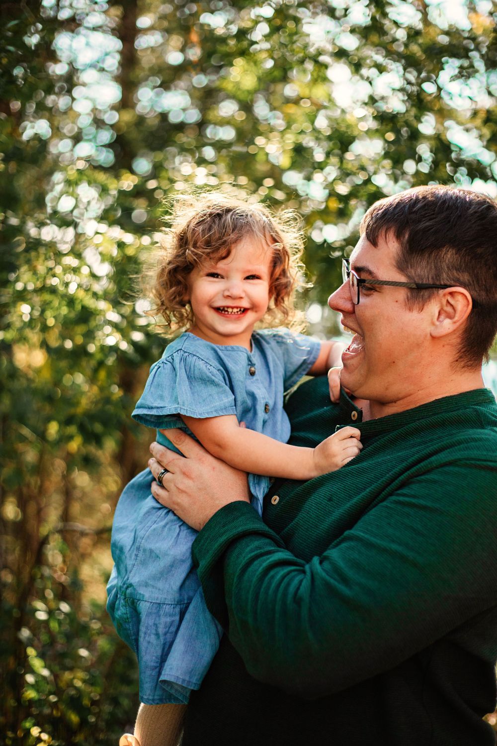 Joyful outdoor portrait against sunlit autumn foliage.