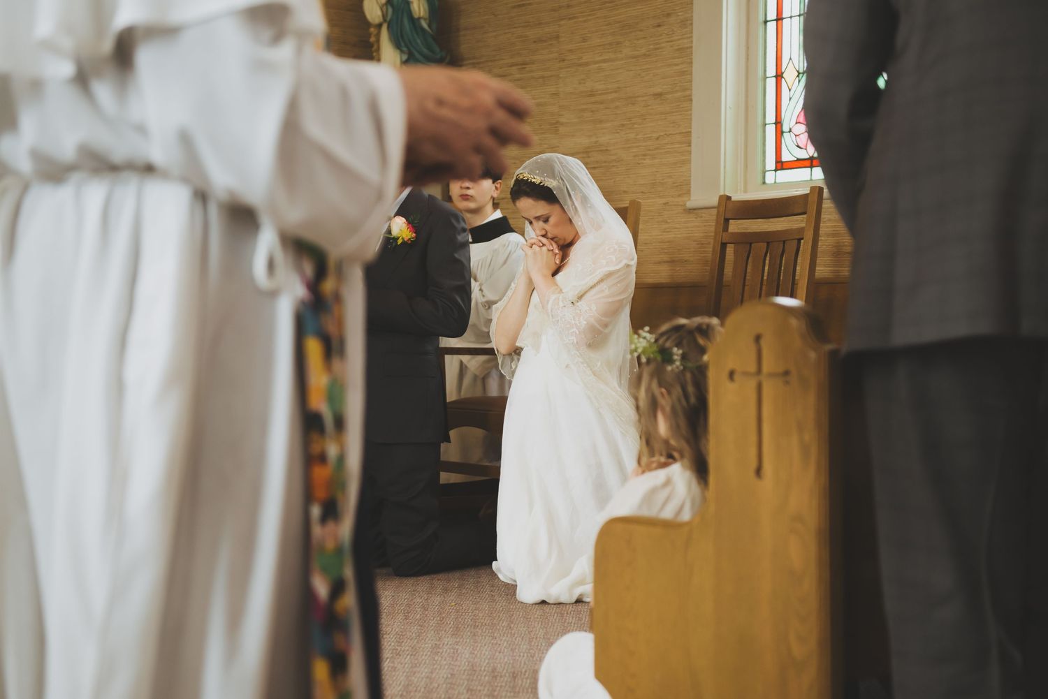 a bride kneels and prayers during her mass wedding ceremony in saanich, bc.