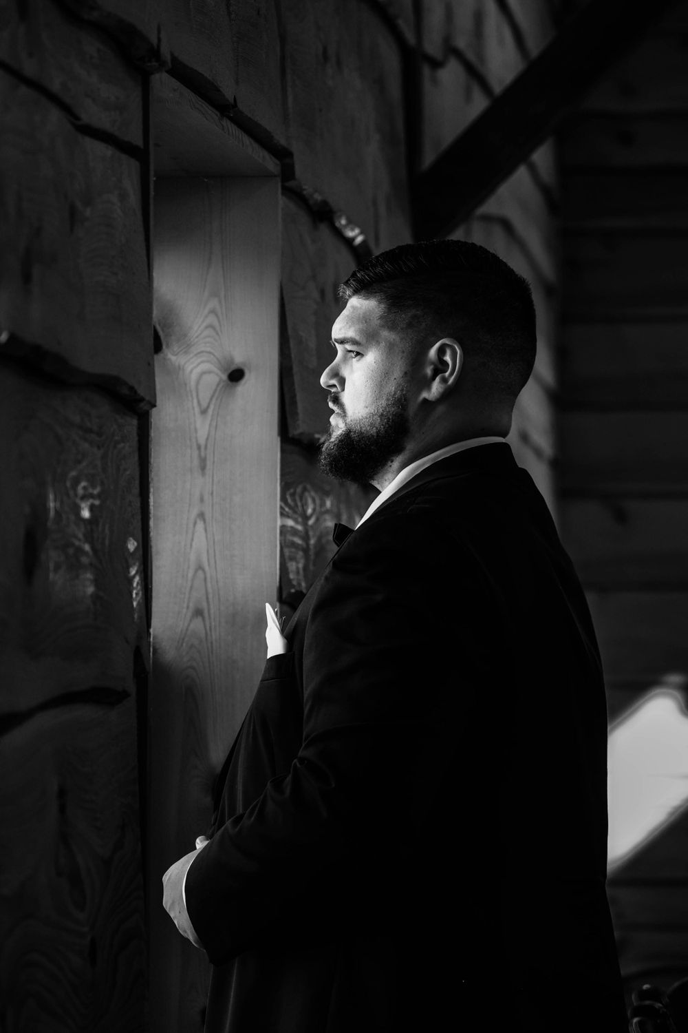 Dramatic black and white side profile of someone in formal attire with light and shadow play.