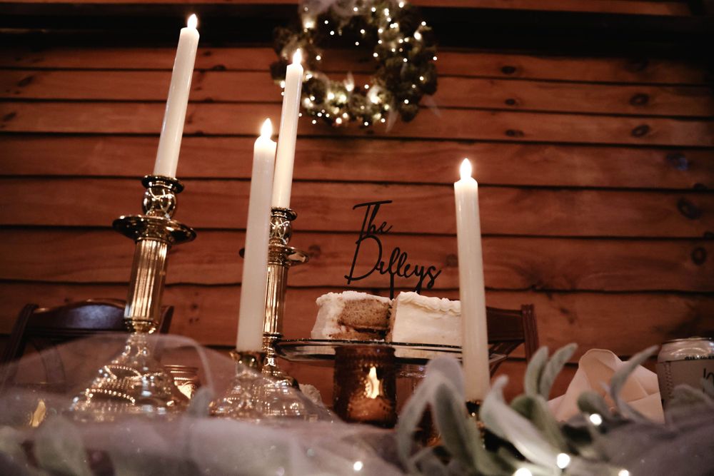 Elegant wedding reception table with lit white taper candles and decorative wreath.