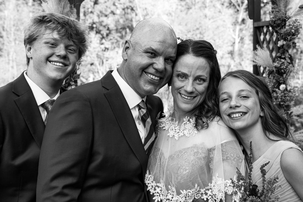 Group poses together for casual black and white portrait outdoors.