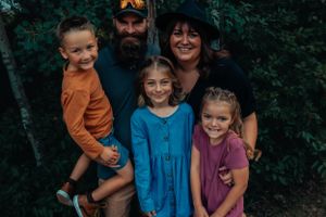 Close-up family photo with green forest background wearing coordinated casual outfits.