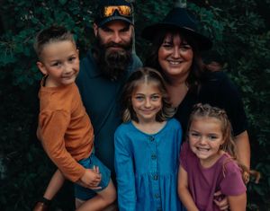 Outdoor family portrait with green foliage background in casual attire.