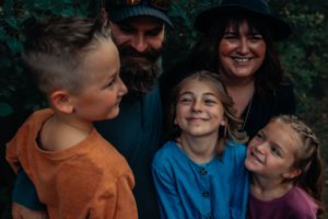 Intimate family photo showing joyful expressions against forest backdrop.
