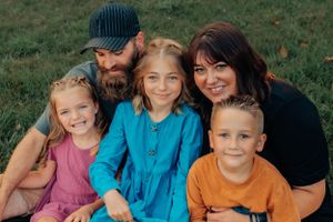 A cheerful outdoor portrait of a group of five people against a natural backdrop.