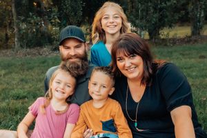 An intimate family portrait taken outdoors with everyone smiling at the camera.