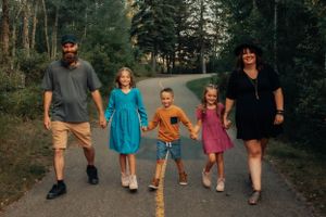 Family walking together on a tree-lined path, wearing colorful casual outfits.