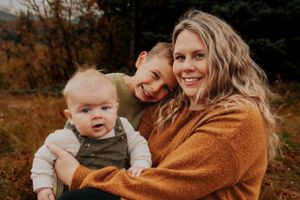 A joyful outdoor autumn portrait featuring warm embraces and laughter against fall foliage.