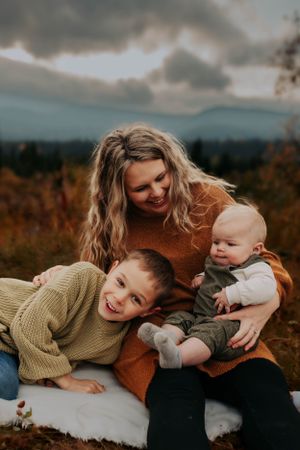 A heartwarming family moment captured outdoors with cozy sweaters against an autumn mountain landscape.
