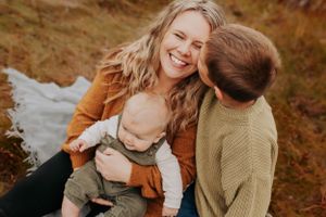 A candid family photo shows tender moments and laughter during an autumn outdoor photoshoot.