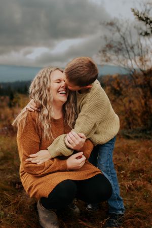 An intimate portrait captures genuine laughter and embraces during a fall outdoor photo session.
