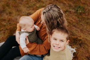 A cheerful outdoor family portrait captures genuine smiles against an autumn backdrop.