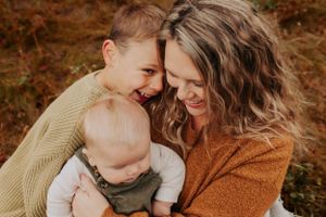An intimate family portrait captures tender moments and smiles during an outdoor autumn photoshoot.