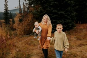 A casual family walking photo showcases autumn colors and cozy sweaters in a mountain setting.