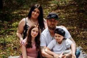 A family cuddles together in a casual outdoor photo session among fallen autumn leaves.