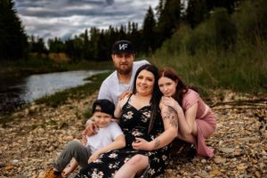 A family photo session near a lake with dramatic cloudy skies in the background.