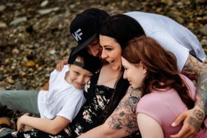 An intimate family photoshoot captures tender moments on a rocky shoreline.