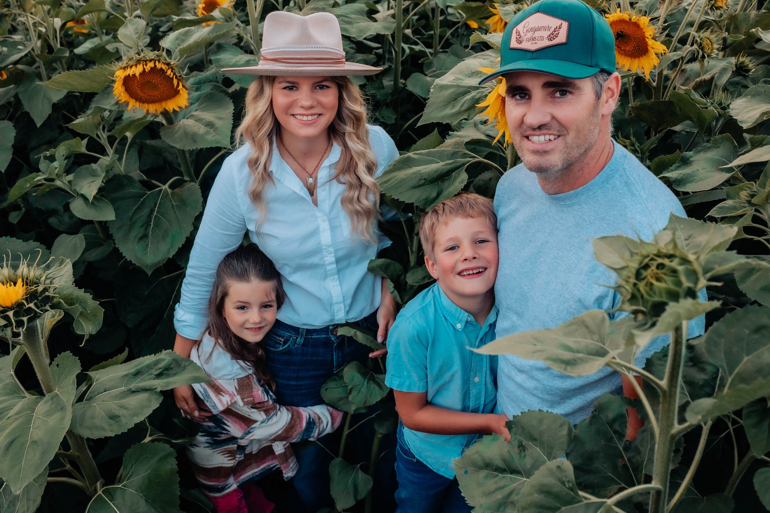 Happy family moment captured in sunflower field with vintage farm equipment.
