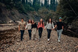 Group walking together on rocky terrain with evergreen forest backdrop.