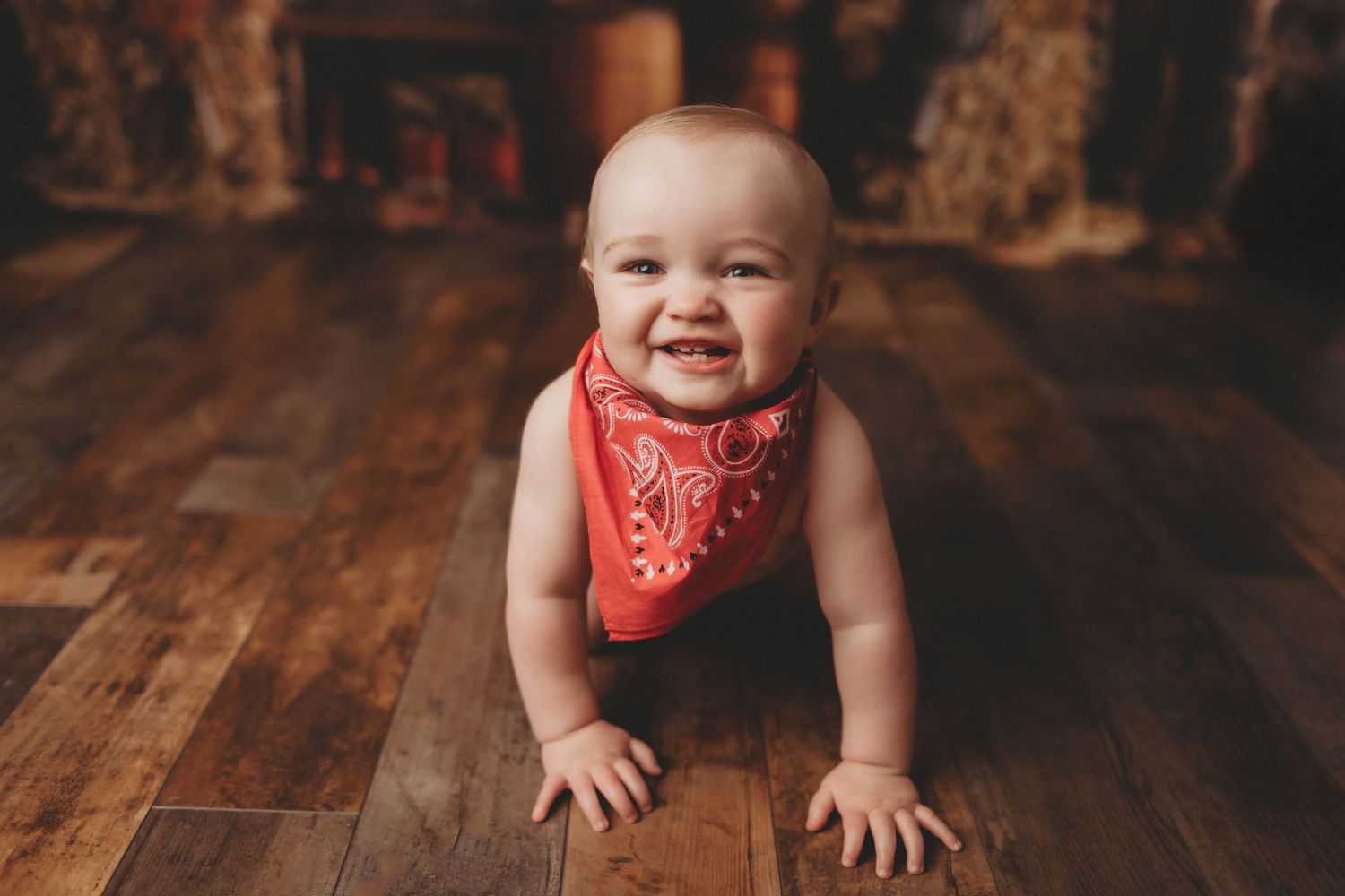Baby in mint dress sits on wooden stool with pastel balloon garland backdrop during first birthday photo session.
