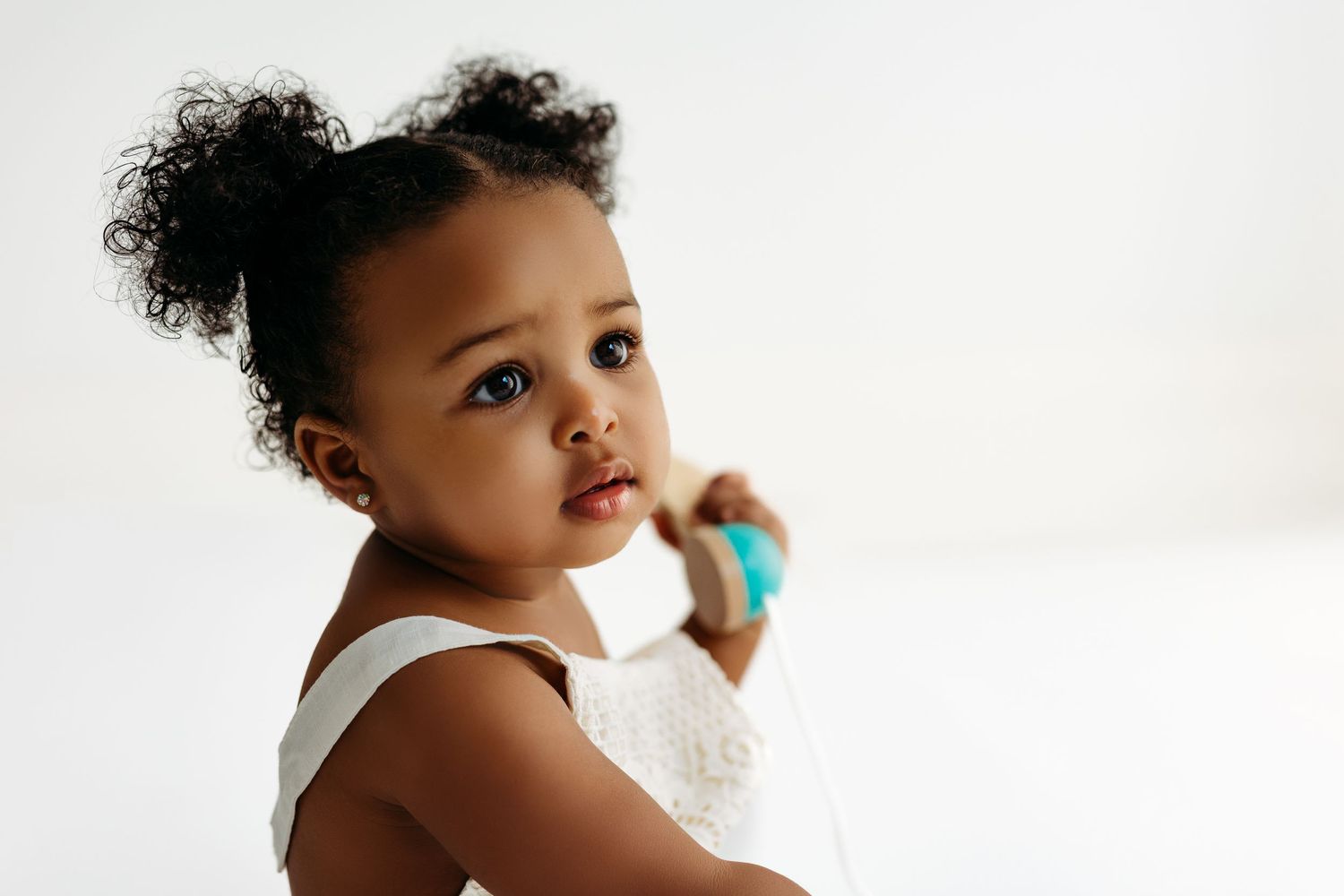 Young child with curly dark hair wearing a white tank top looks to the side against a light background.
Rashinphotography-Nova photographer