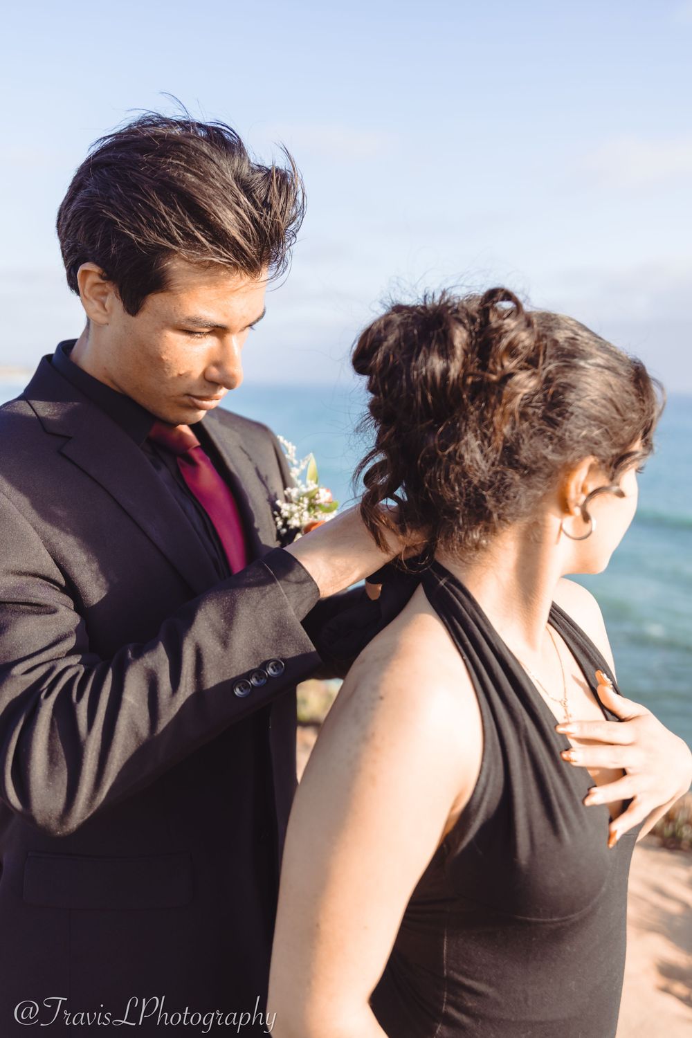 Couple in formal attire sharing a moment by the ocean.