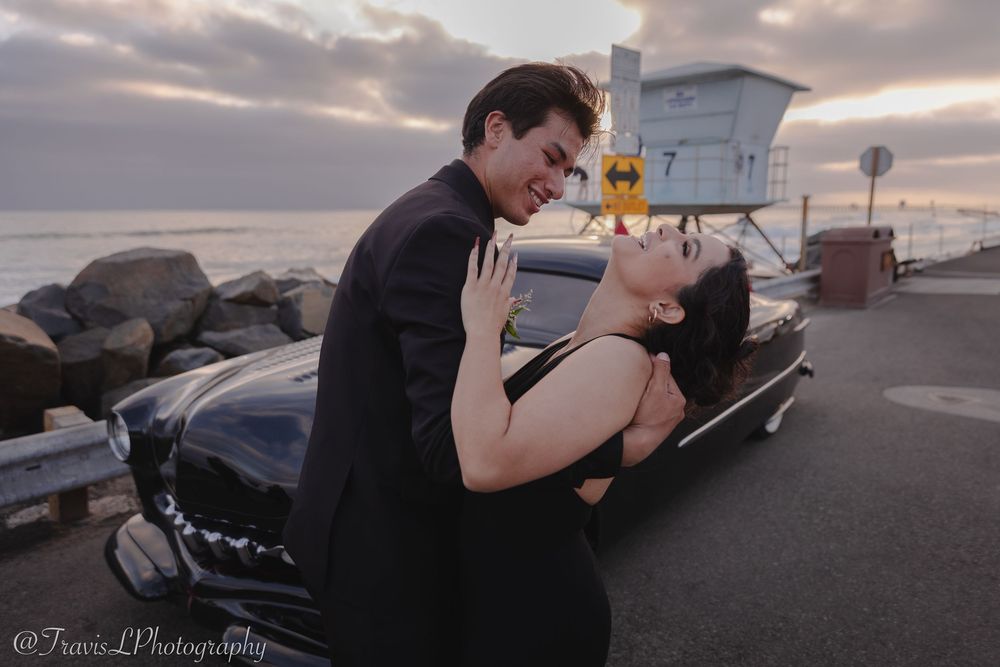 Romantic sunset photoshoot with couple posing near parked cars.
