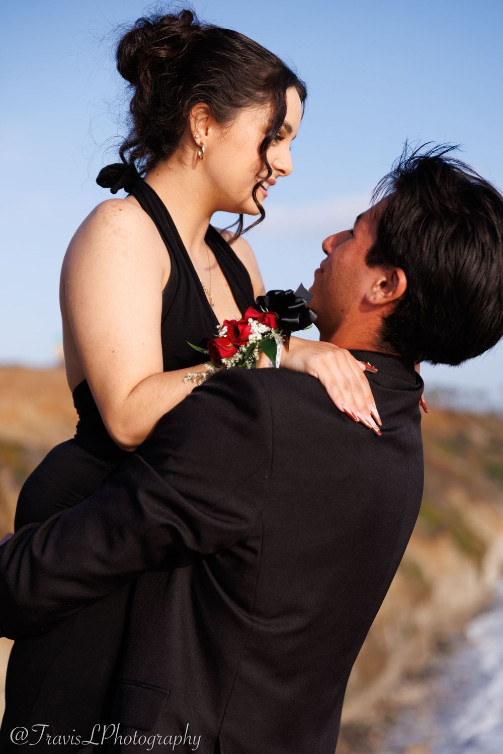 Couple sharing playful moment during sunset photoshoot by ocean cliffs.