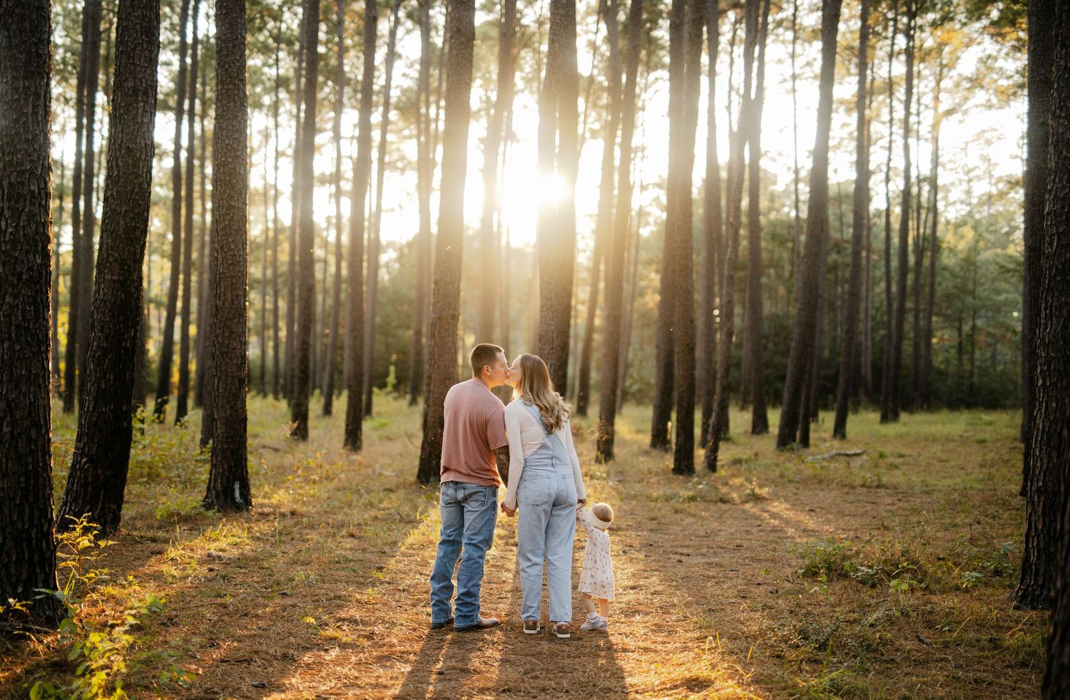 Sunset forest wedding photography with sunlight streaming through pine trees.