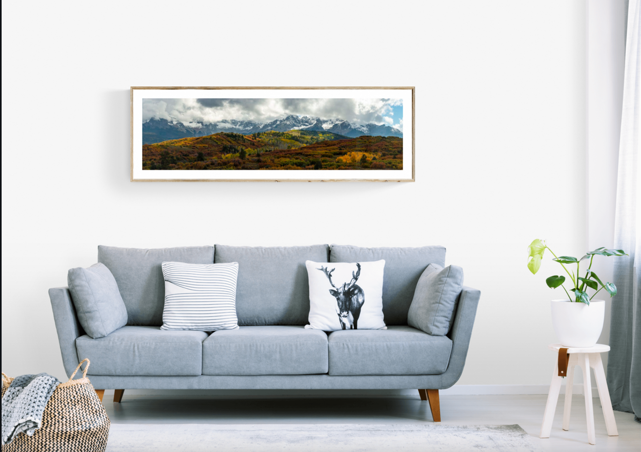 Sample mountain art on the wall above a couch in a living room