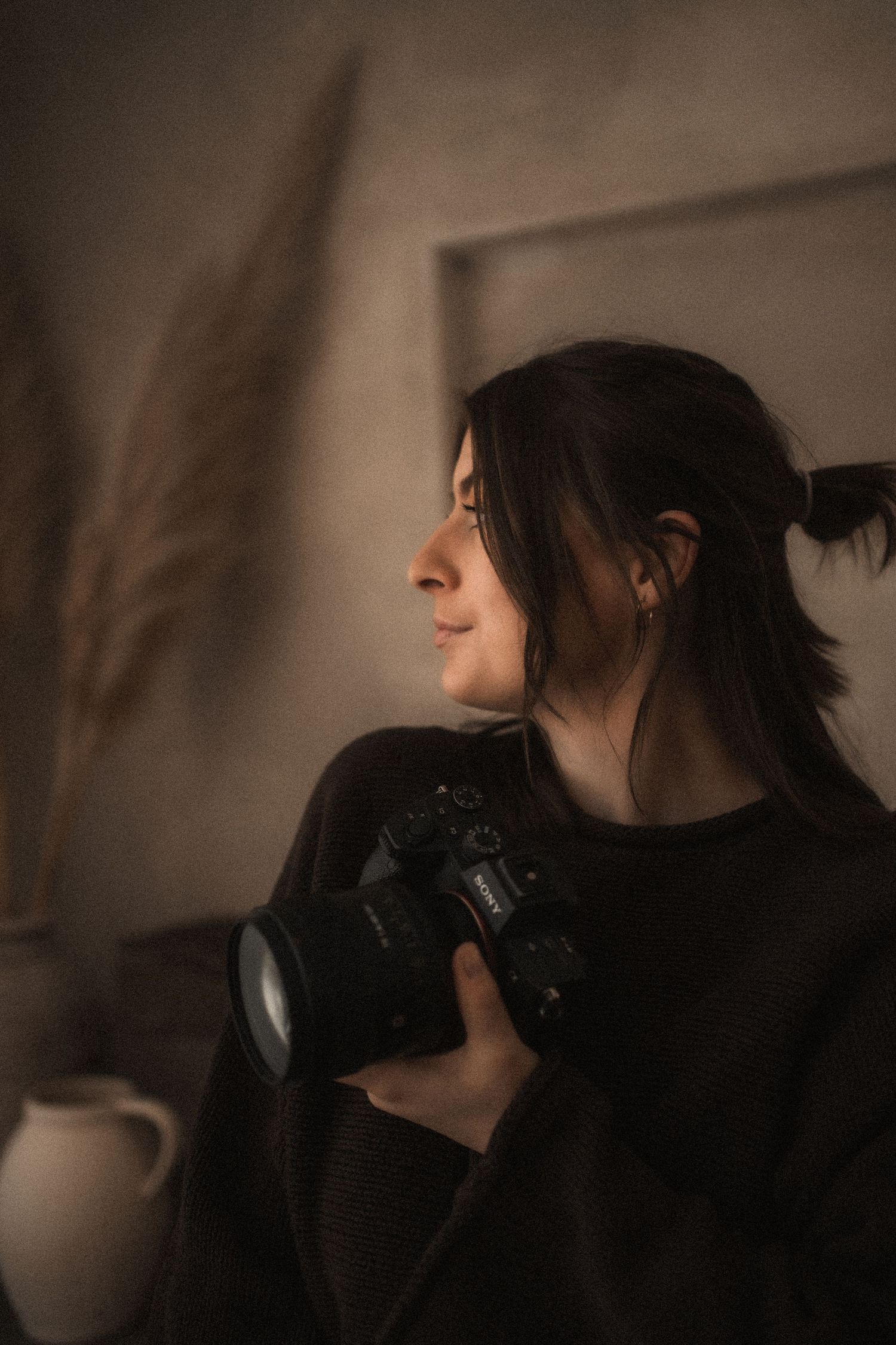 Casual portrait of a photographer sitting on a white stool against a light curtain backdrop.