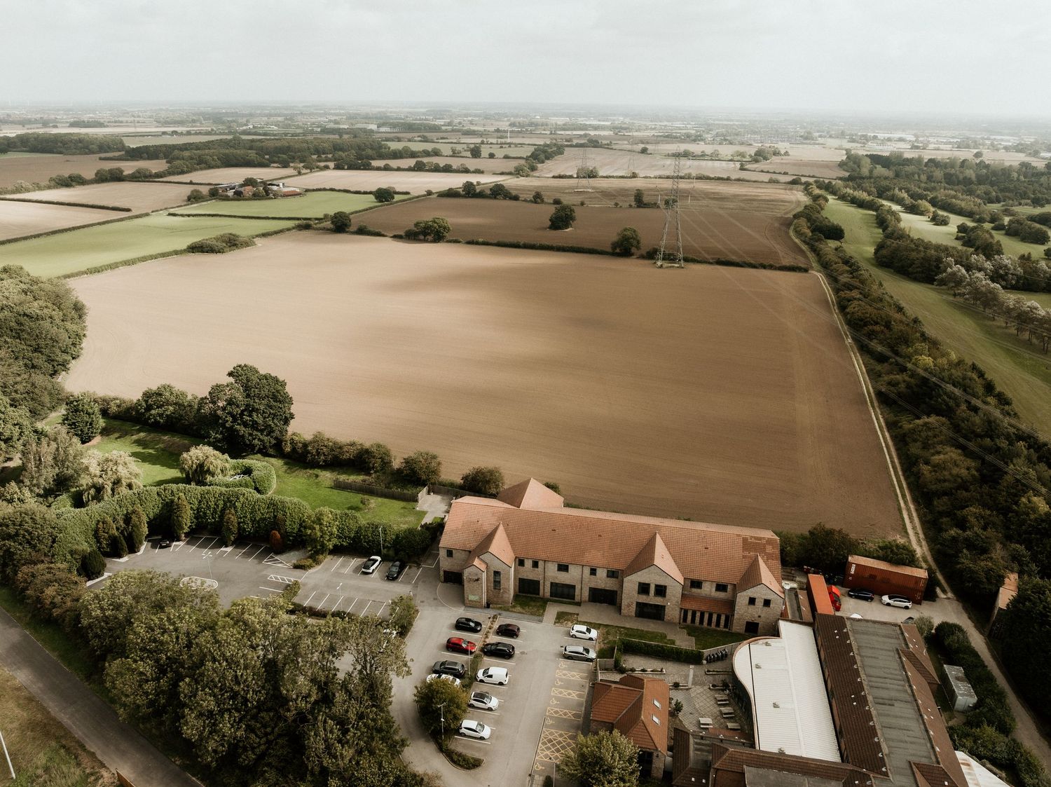 Aerial drone view of a rural wedding venue surrounded by farmland and countryside.