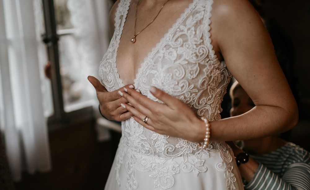 Bride in a white lace V-neck wedding dress wearing a pearl bracelet.