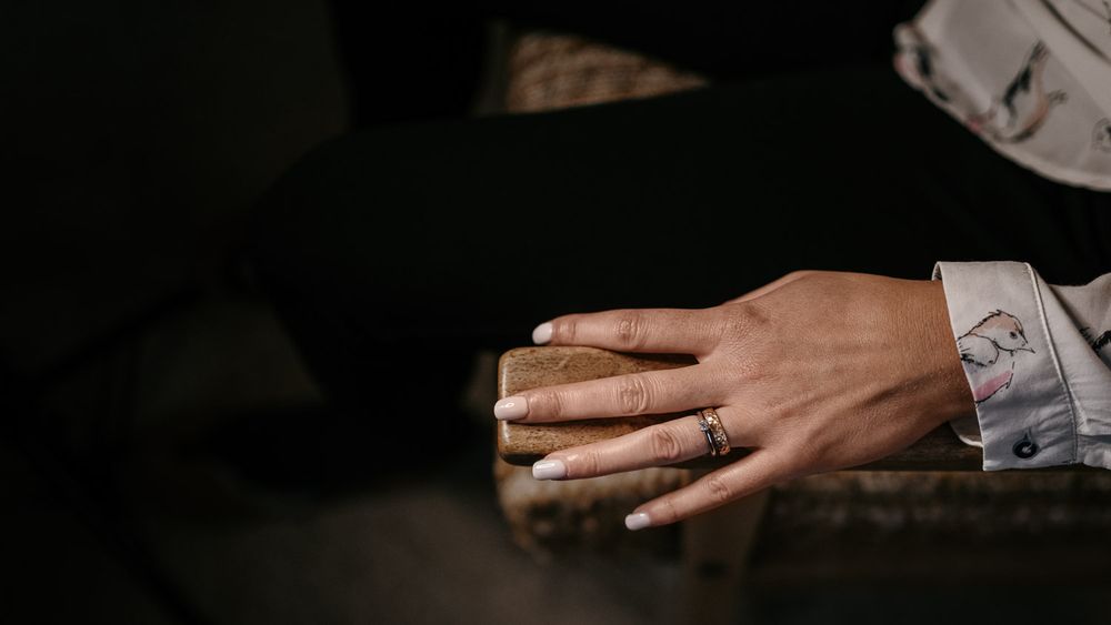 Close-up of bride and groom's hands intertwined, featuring a delicate ring on the bride's finger.