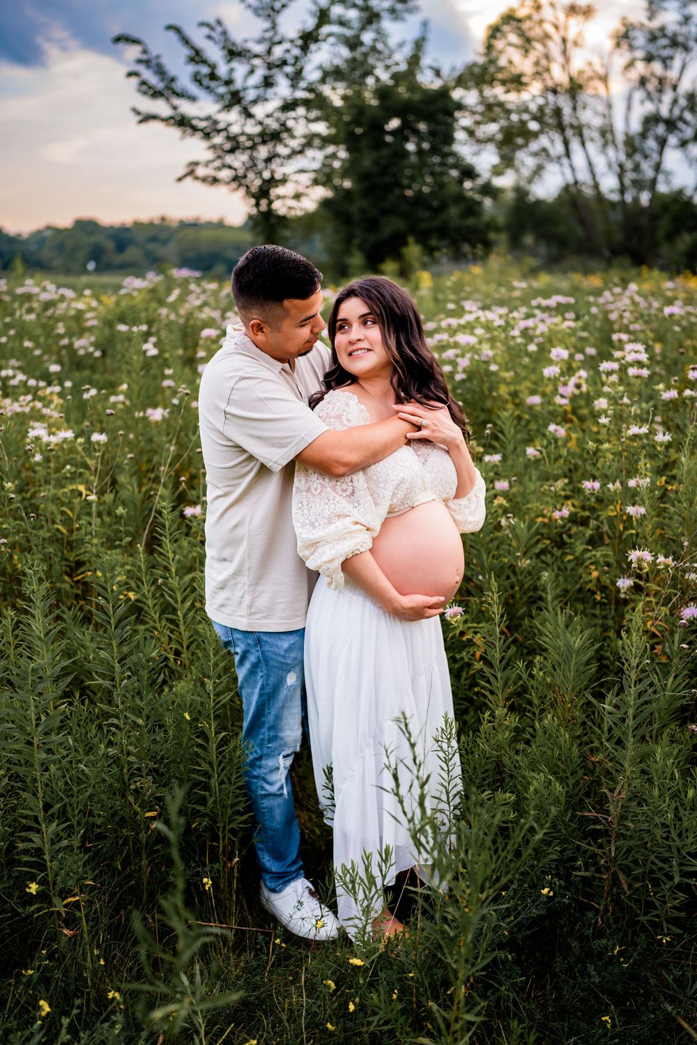 A maternity photo in a wildflower field during golden hour.