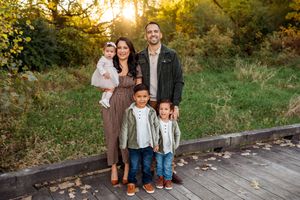 A group poses for photos in a scenic outdoor setting during golden hour with fall foliage in the background.