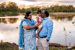 A family sharing a tender moment by a lake during sunset.
