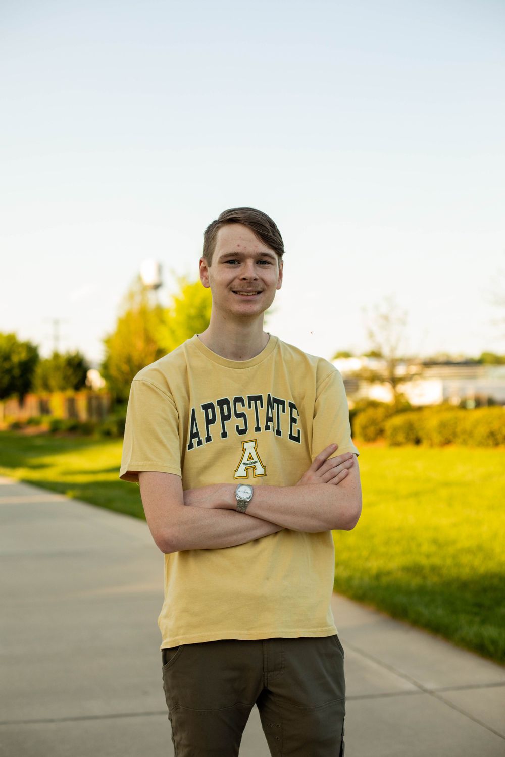 Student wearing yellow Appstate shirt poses outdoors in sunlit setting.