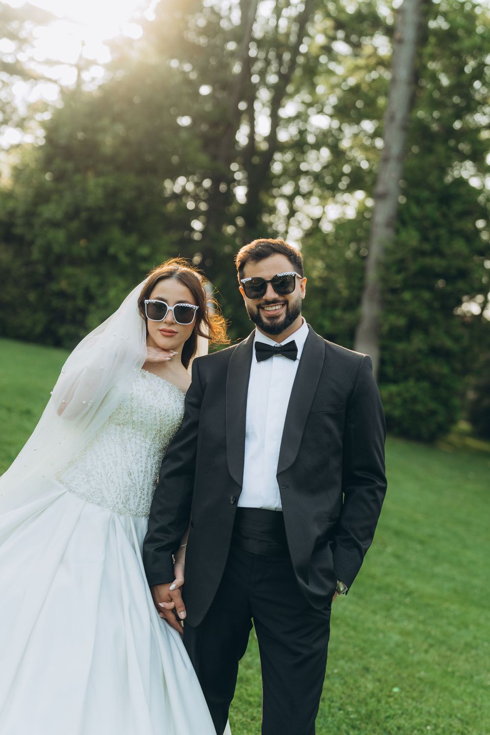 A bride and groom share joyful candid moments together on a grassy hillside during their wedding photo session.