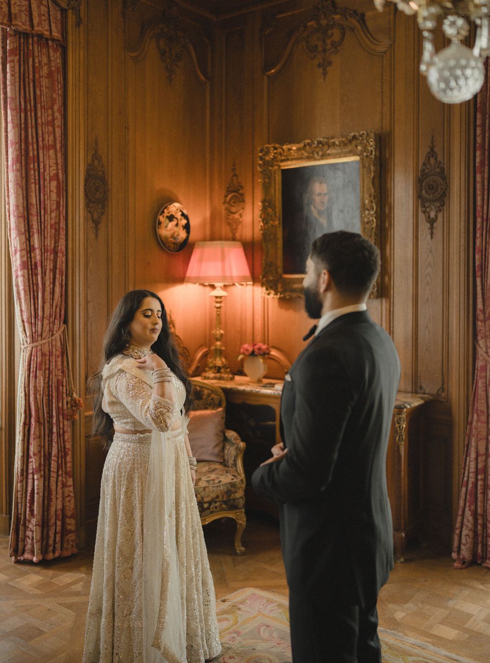A couple shares an intimate moment in a vintage-decorated room with warm lighting and ornate furniture.