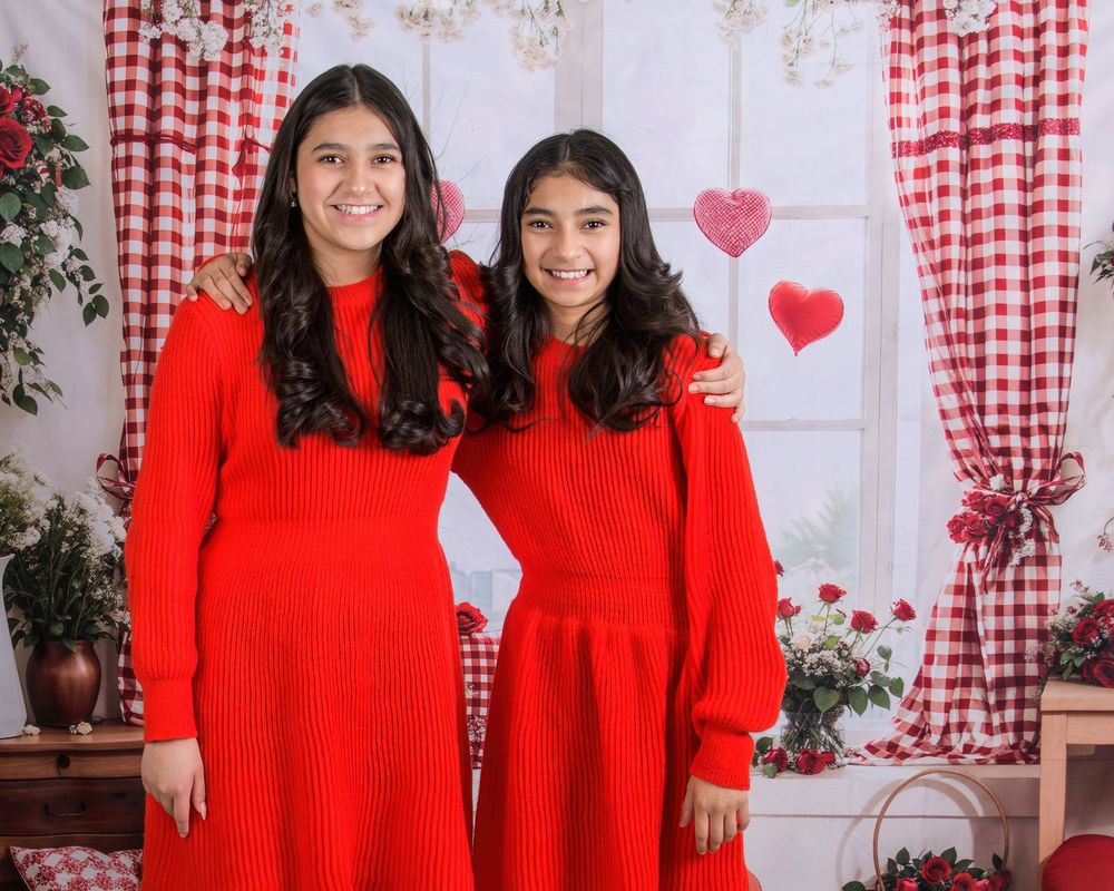 Red and white decorated Valentine's photo studio setup with gingham curtains and heart decorations.
