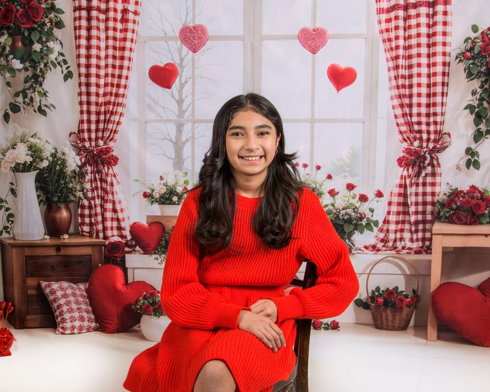 Valentine's Day themed photo session with red dress and gingham curtains in a cozy indoor setting.