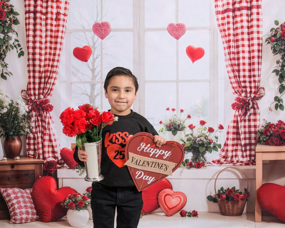 Red and white checkered Valentine's Day photo backdrop with heart decorations and rustic window setting.