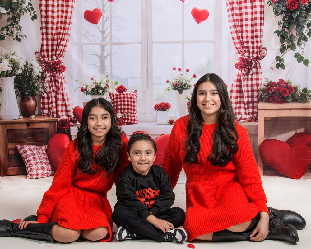 Red and white Valentine's day photo session setup with gingham curtains and floral decorations.