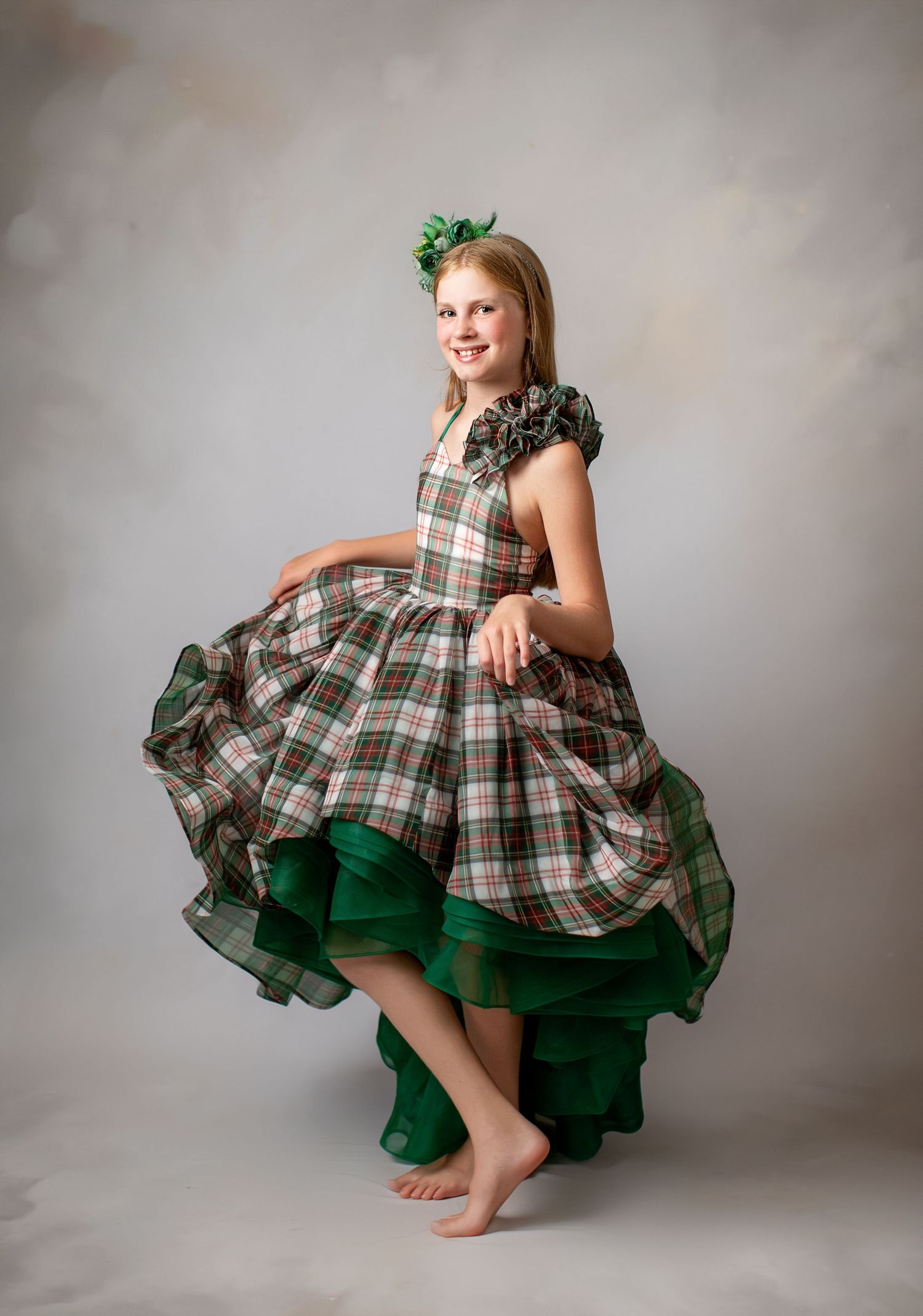 Emerald green velvet dress creates dramatic silhouette against smoky dark green backdrop.