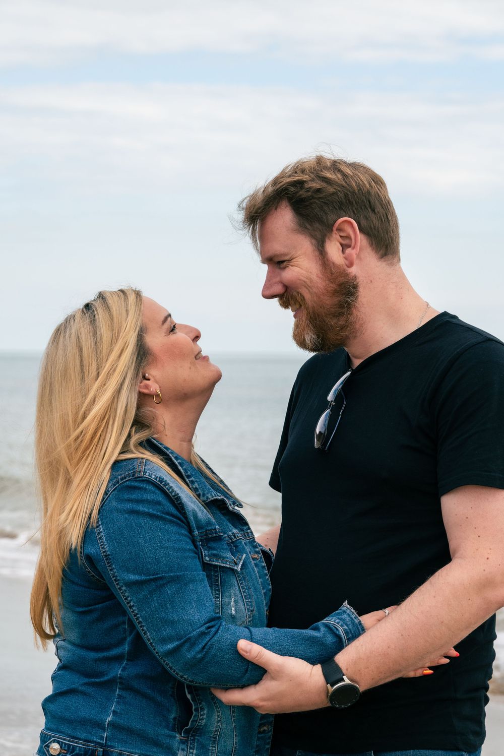 Couple embracing and laughing by the ocean.